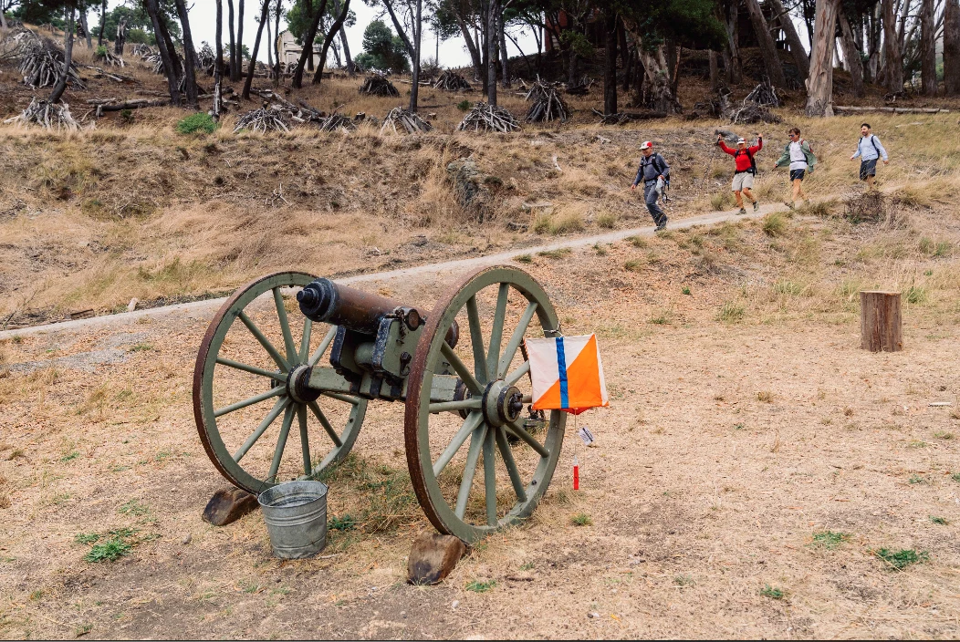 The Angel Island cannon with an orange-and-white orienteering flag beside the race trail.