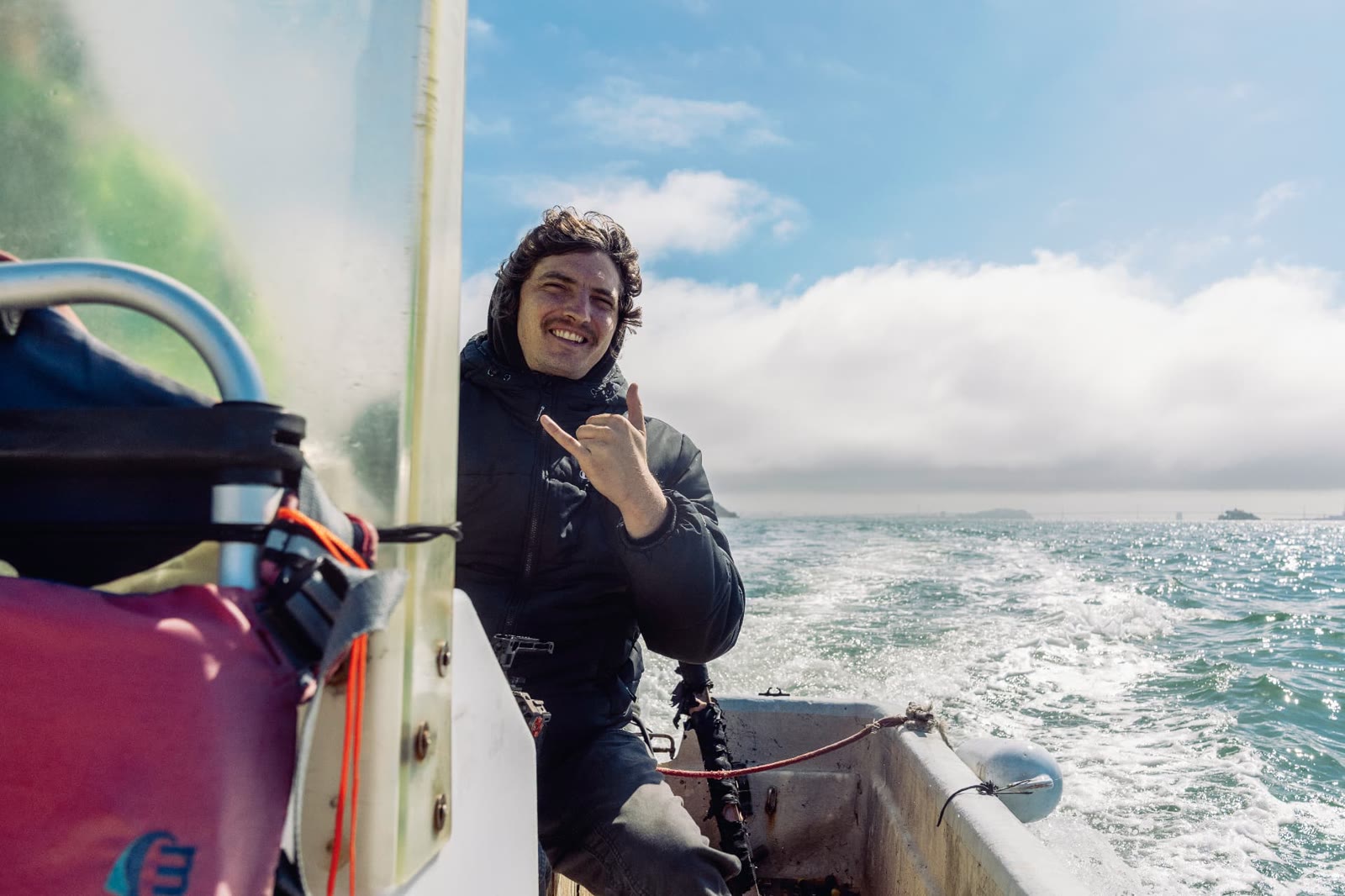 Smiling crew member giving a shaka sign aboard a boat on the bay